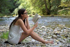 Mulher lendo um livro em uma área repleta de natureza
